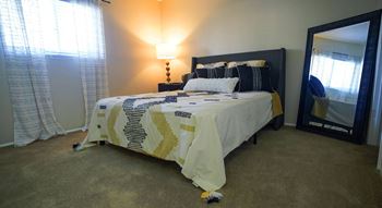 A bedroom with a bed, lamp, and window.